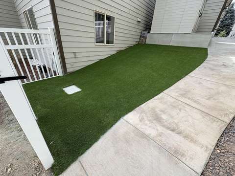 A strip of artificial turf running down a side yard between a white gate and a concrete walk, in west Greeley, Colorado